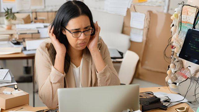 A frustrated Etsy seller sits at a cluttered desk, laptop open, encountering persistent software bugs disrupting their online shop management, surrounded by error messages and help guides.